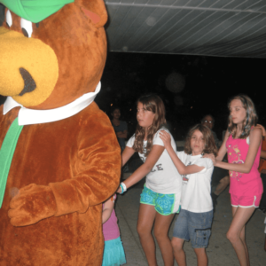 Yogi Bear leading a conga line of kids