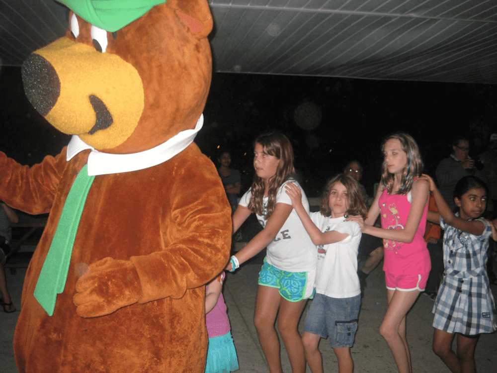 Yogi Bear leading a conga line of kids